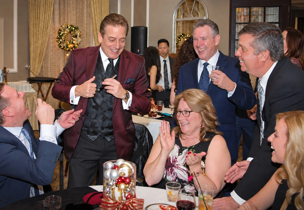 Mike Thornton performing magic in a burgundy jacket